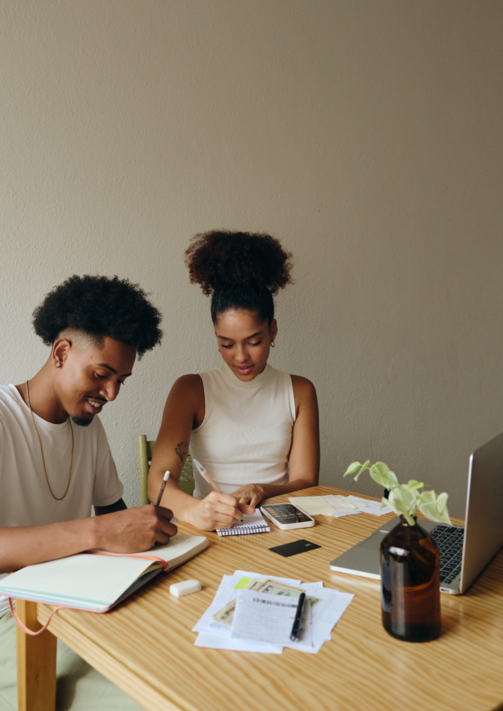 Couple working through their financial budget, identifying areas to save so they can invest after their first session with Money Moxie Mentor for their personal financial coach.